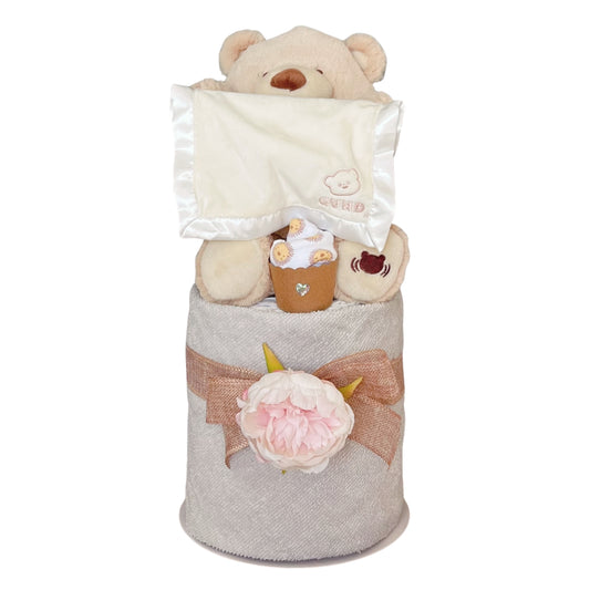 GUND animated Peek-A-Boo teddy bear 1-tier baby nappy cake gift set featuring a textured receiving blanket, rustic burlap ribbon, and a decorative pink flower.