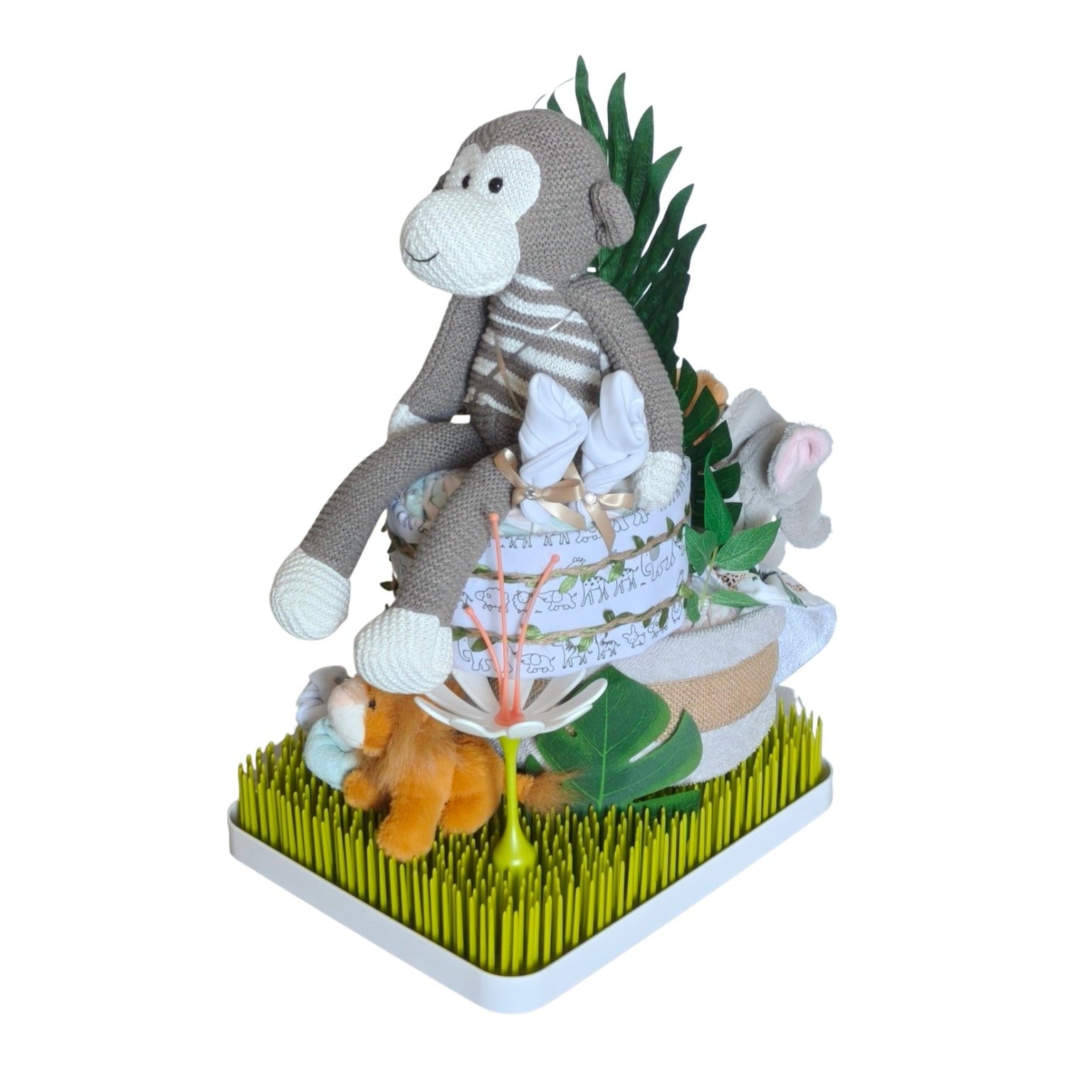 Side view of the  Monkey in the jungle nappy cake featuring a knitted monkey, plush lion, jungle leaf décor and Boon Grass drying rack.
