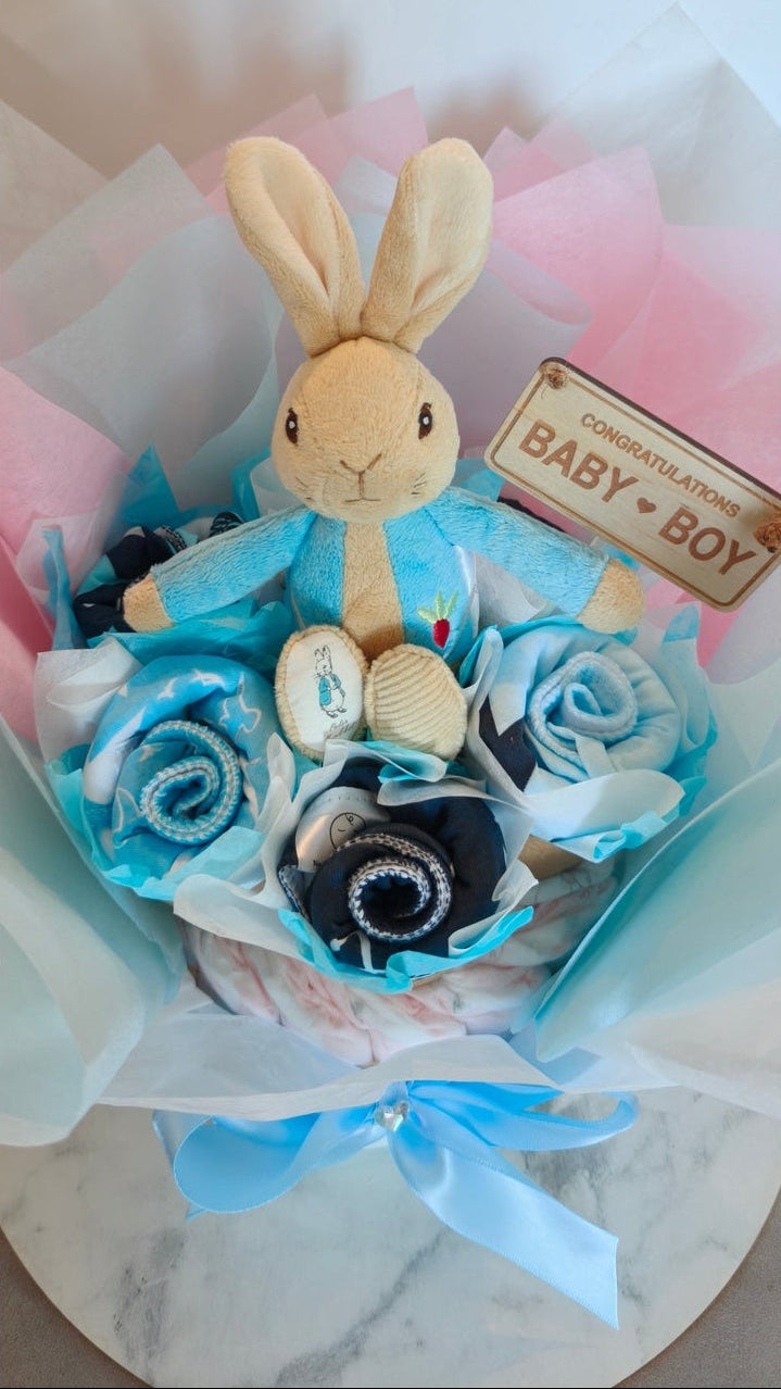 Top view of Peter Rabbit Little Explorer baby boy bouquet nappy cake showing plush bunny toy and a wooden Congratulations sign.