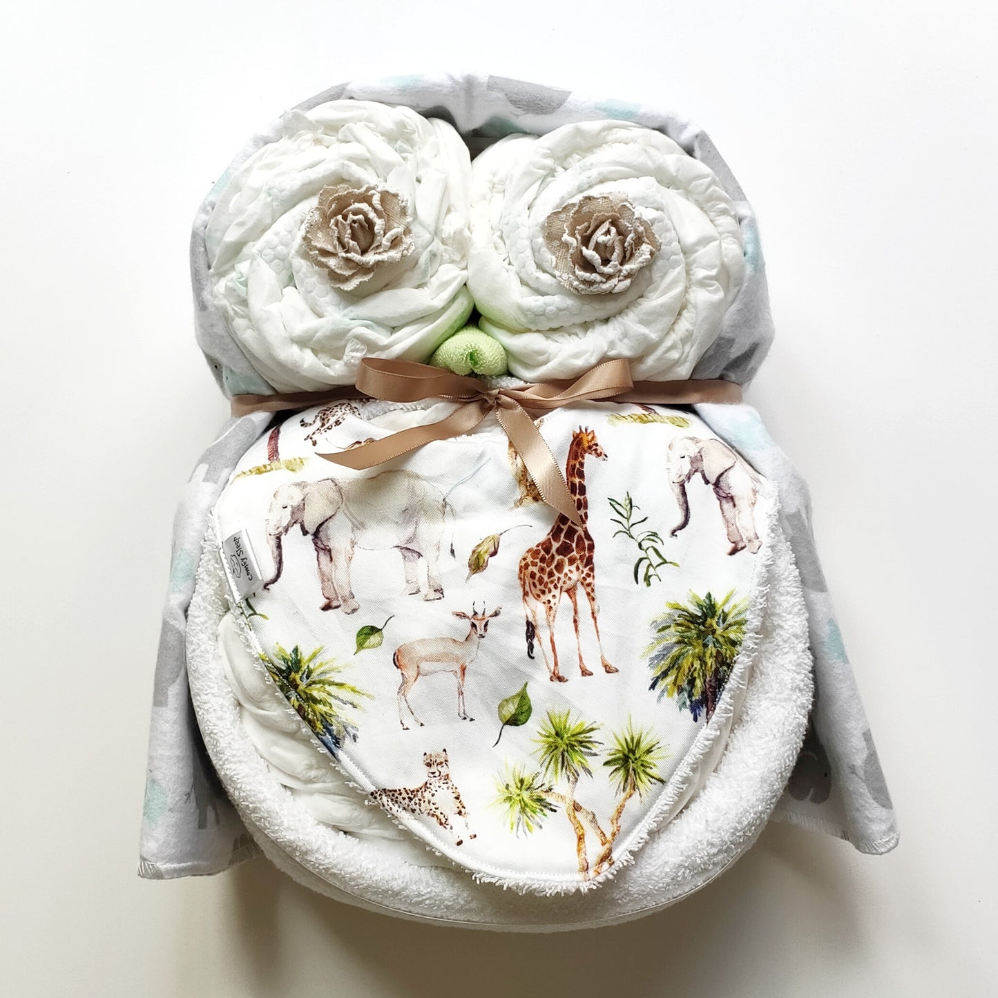 Woodie unisex baby owl nappy cake gift set featuring rolled nappies, Nappy Terry Towel, baby bib, receiving blanket, and a tan ribbon bow.